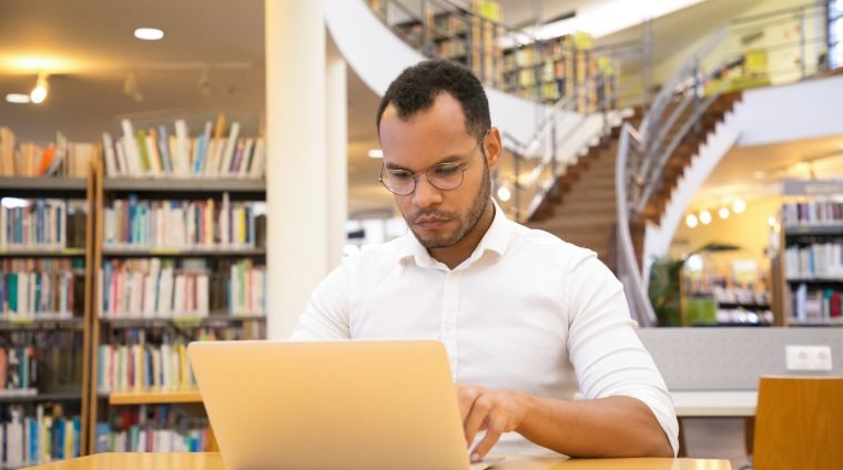 focused-young-man-typing-laptop-public-library_74855-4240